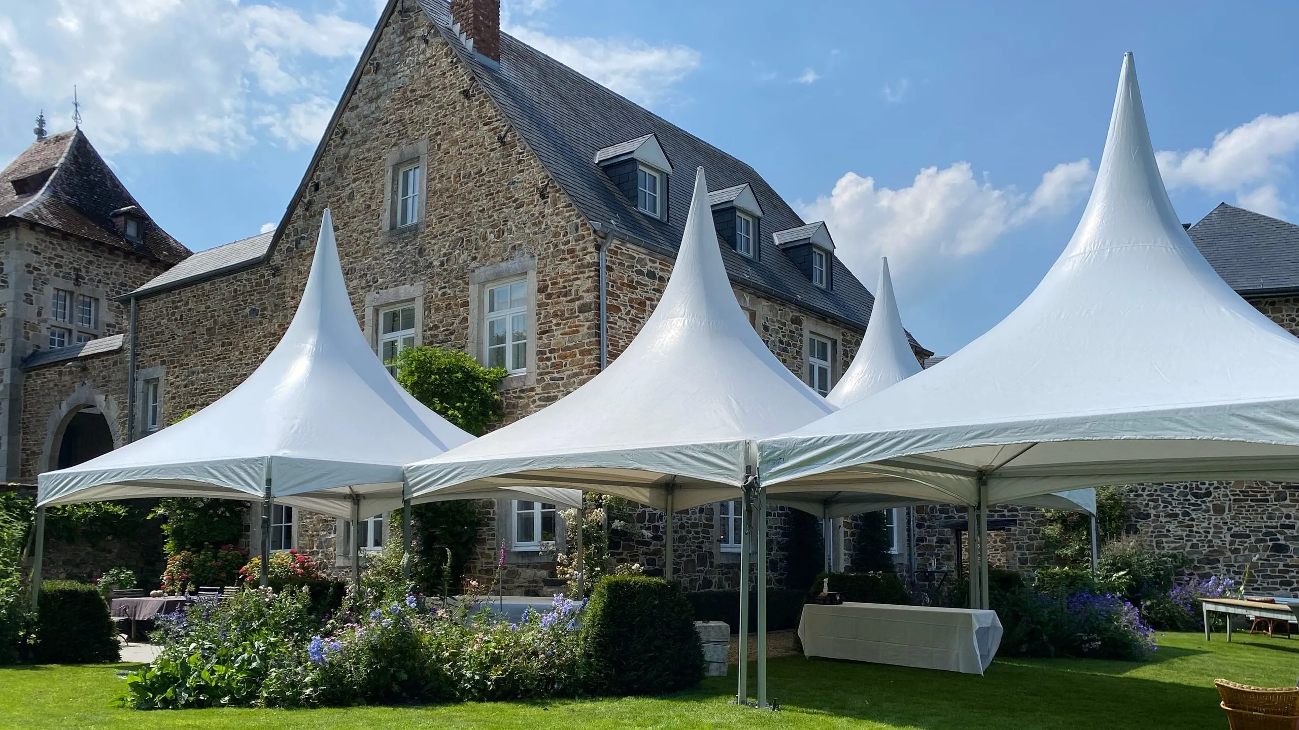 Trois pagodes blanches devant une bâtisse en pierre, jardin fleuri