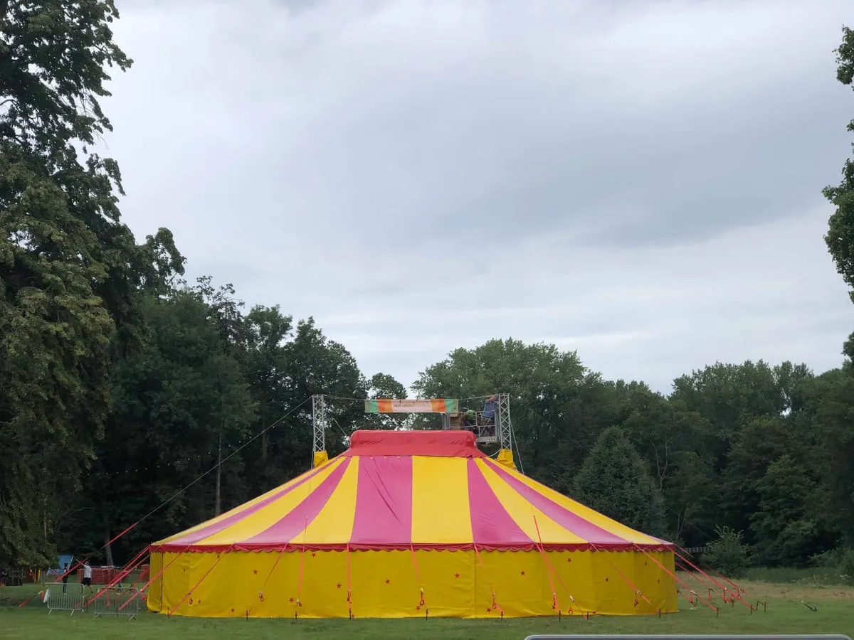 Chapiteau de cirque jaune et rose dans une clairière