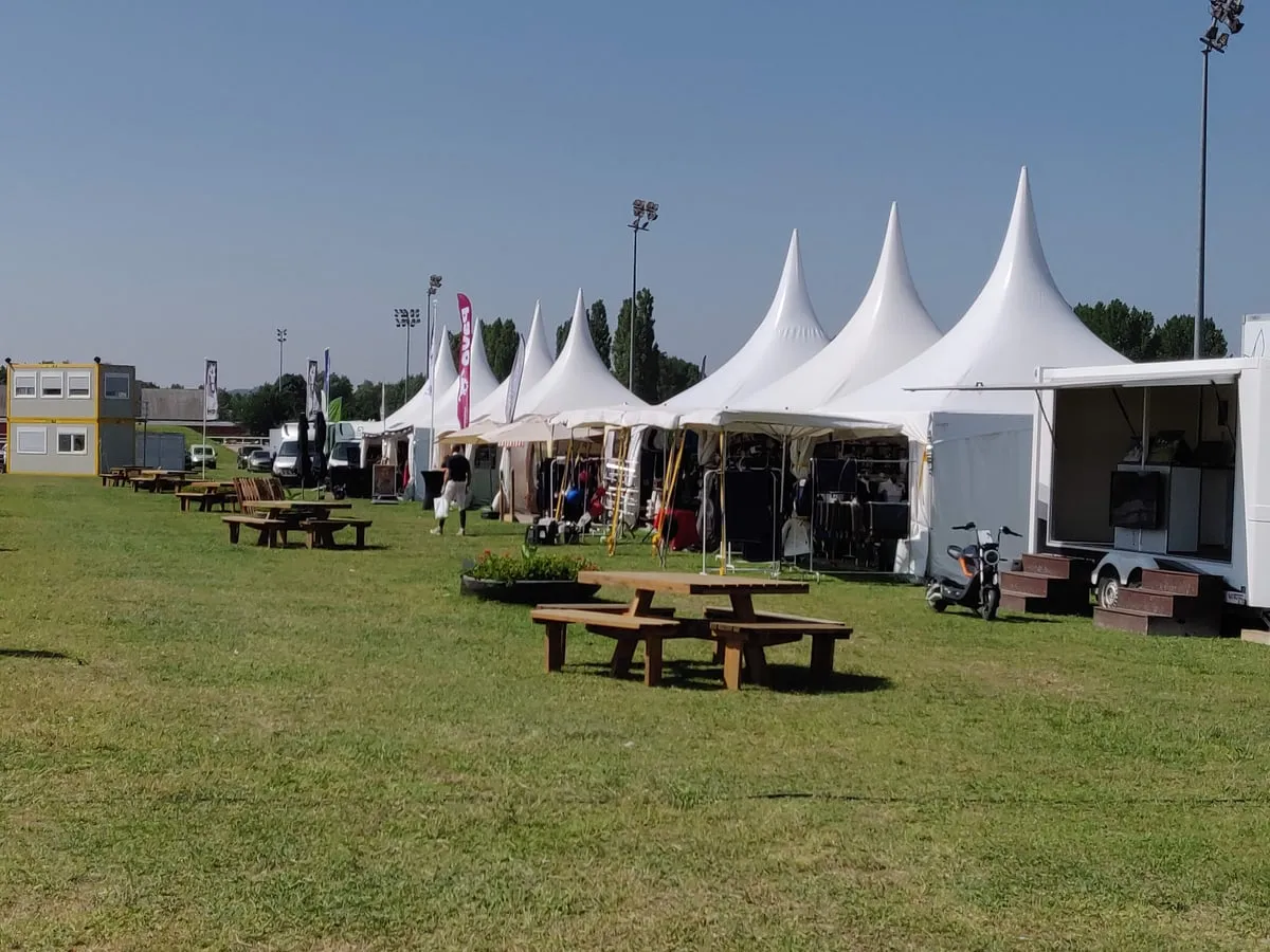 Pagodes blanches alignées sur une pelouse, tables de pique-nique devant